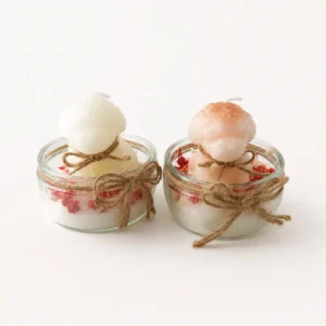 Deux bougies boule blanche et rosée dans des pots de verre avec baies séchées